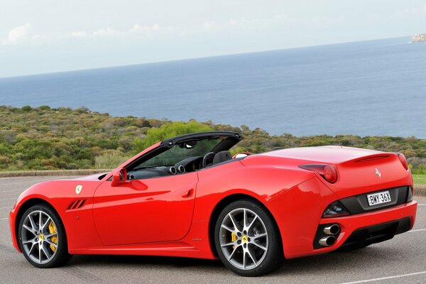 Czerwone ferrari Kalifornia na wybrzeżu