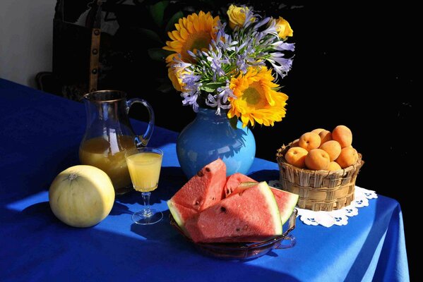 Martwa natura na stole bukiet w wazonie, arbuz, melon i dzbanek z sokiem