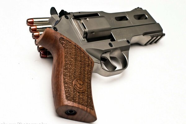 Na białym tle znajduje się rewolwer z nabojami